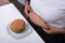 Woman Pinching Her Fatty Stomach With Hamburger On Table