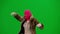 Woman in pink balaclava, tiger fur coat and dress walking and dancing merrily with her hands up. Woman freak on green