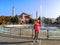 Woman in pink and beige clothes takes a photo on a smartphone on the backdrop of Church of the Holy Wisdom in Istanbul. Beautiful