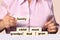 Woman in pink clothes stacks a pyramid of light wooden bars, cubes with words on the theme of family, photograph, text, close-up,