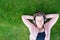 Woman in pink coat, black top and jeans listens to music / audiobook and resting on meadow / green grass on sunny spring warm day