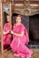 Woman in pink dress with decorations on head sits