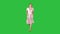 Woman in pink dress with hands in pockets is walking towards the camera on a Green Screen, Chroma Key.