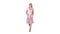 Woman in pink dress with hands in pockets is walking towards the camera on white background.