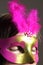 Woman with a pink an gold colored eye mask with feathers