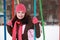 Woman in pink hat sitting on swing in winter