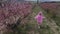 woman in a pink hooded dress with flowers walks through a peach field
