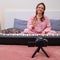 A woman in pink pajamas is broadcasting an online piano game on the Internet. Smiling woman pianist showing hand gesture welcome,