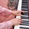 A woman in pink pajamas and a funny pet learn to play the piano on a home bed