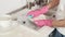 A woman in pink rubber gloves foam washes a plate in a large sink at home