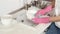 A woman in pink rubber gloves foam washes a plate in a large sink at home