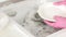 A woman in pink rubber gloves washes a plate with tap water in a large sink at home