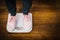 Woman with pink sneakers on bathroom weight scale