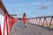 A woman in a pink sweat suit runs across the bridge