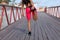 A woman in a pink sweat suit stretches on a bridge before jogging