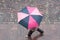 Woman with pink umbrella on cobbles place