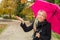 Woman with pink umbrella enjoying rainy autumn weather