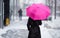 Woman with pink umbrella walking on snowy day