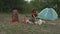 Woman Pitching a Tent near Her Camp Gear in the Forest