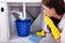 Woman Placing Bucket Under Water Leaking From Sink Pipe