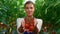 Woman plantation worker showing vegetables in countryside farmland portrait