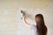 Woman plastering the walls with finishing putty in the room