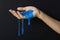 Woman playing with blue slime on black background, closeup. Antistress toy