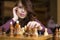 Woman playing chess indoor and thinking position, find winning move, strategy