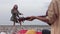 A woman playing guitar by the sea and her little daughter happily clapping her hands