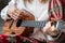 Woman playing Hawaiian guitar, sings a song on vintage ukulele at home. Selective focus