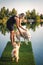 Woman playing with her dogs on pier at lake in hot summer day