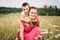 Woman playing with little son in field with weeds and meadow flowers on summer day. Carefree mother having fun with child on