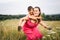 Woman playing with little son in field with weeds and meadow flowers on summer day. Carefree mother having fun with child on