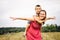 Woman playing with little son in field with weeds and meadow flowers on summer day. Carefree mother having fun with child on