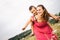 Woman playing with little son in field with weeds and meadow flowers on summer day. Carefree mother having fun with child on