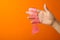 Woman playing with pink slime on orange background. Antistress toy