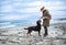 Woman playing with rottweiler dog in cold weather on the beach