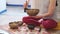 Woman playing on Tibetan singing bowl while sitting on yoga mat. Vintage tonned. stock footage. Slow Motion video. Close