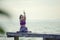 Woman playing yoga on wooded pier against plain sea background