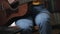 A woman plays a guitar, tapping her foot to the beat. Camera movement from bottom to top. Learning to play musical instruments