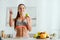 Woman pointing with finger and holding apple near plate with fruits