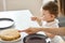 Woman pointing to pancakes, asking her child to taste them