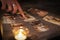 A woman points at tarot cards by a candle, in the darkness