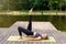 A woman by a pond in a park in summer, does yoga