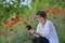 Woman In A Poppy Field Reading A Tablet Book