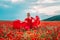 Woman poppy field red dress. Happy woman in a long red dress in a beautiful large poppy field. Blond stands with her