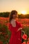 Woman poppy field red dress sunset. Happy woman in a long red dress in a beautiful large poppy field. Blond stands with