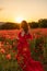 Woman poppy field red dress sunset. Happy woman in a long red dress in a beautiful large poppy field. Blond stands with