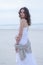 Woman Portrait on the beach. Happy beautiful curly-haired girl full-length, the wind fluttering hair. Spring portrait on the beach