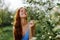 Woman portrait beautifully smiling with teeth spring happiness in nature against a green tree hand touch tenderness